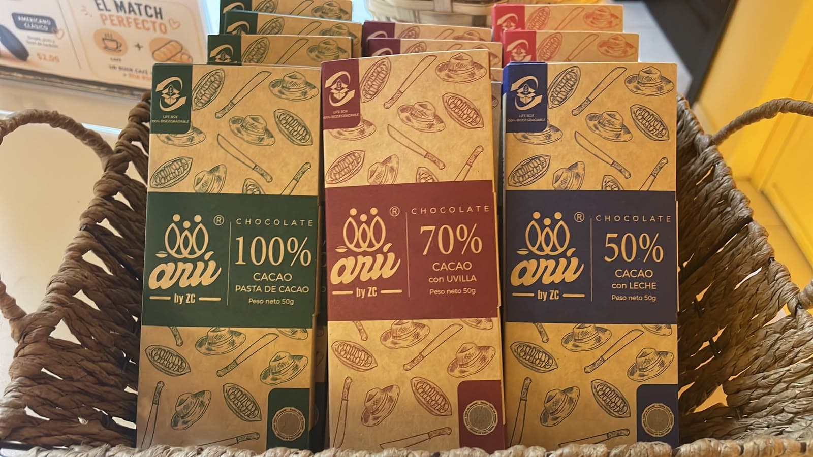 Three Arú chocolate bars in 100%, 70%, and 50% cacao packaging in a woven basket.